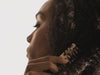 Black girl combing her hair with wide tooth comb.
